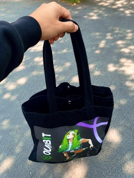A person holds a black tote bag featuring a colorful graphic design with the word 'KUBIT' on it.
