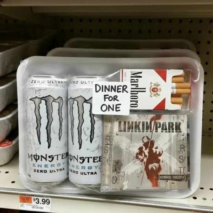 A novelty 'Dinner For One' gift pack on a store shelf containing two Monster Energy Zero Ultra cans, a pack of Marlboro cigarettes, and a Linkin Park 'Hybrid Theory' CD, priced at $3.99.