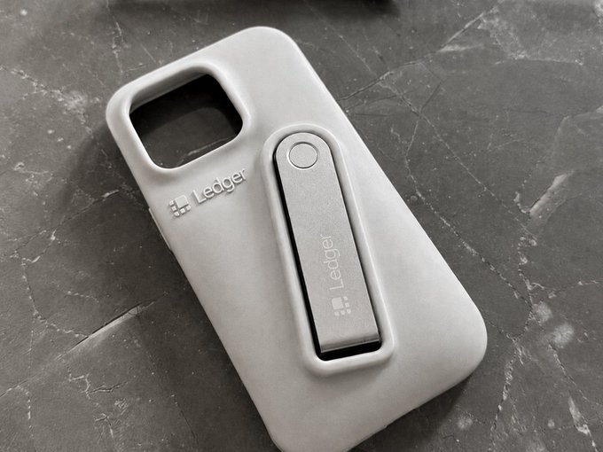A gray Ledger phone case featuring a built-in stand on a dark marble surface.