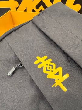Close-up of a gray tracksuit with yellow 'Yeezy' graffiti-style text on the pants and a zipper pull visible.