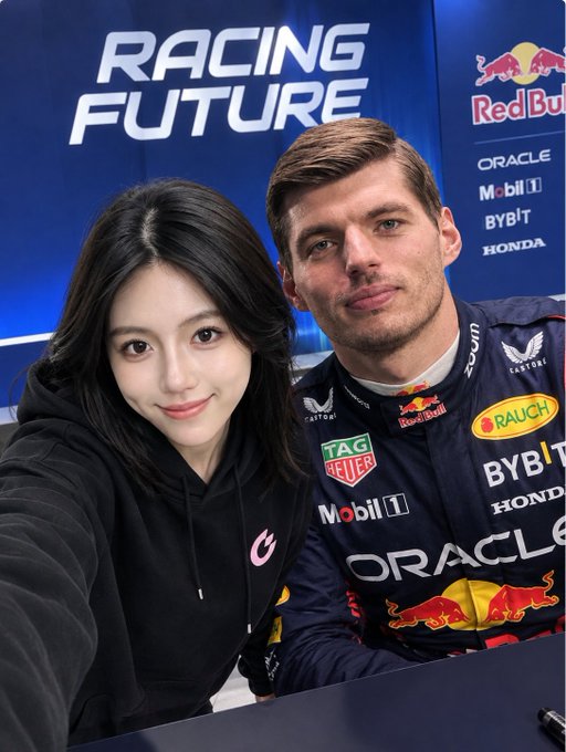 A selfie of a woman in a black hoodie posing with Formula 1 driver Max Verstappen in his Red Bull Racing uniform, with 'RACING FUTURE', 'Red Bull', 'ORACLE', 'Mobil 1', 'BYBIT', and 'HONDA' logos visible in the background.