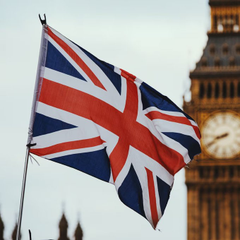 The image shows a Union Jack flag waving in front of the iconic Big Ben clock tower in London, symbolizing the United Kingdom's legal and national identity. This visual directly relates to the news about London's High Court ruling on the £3.8 billion Bitcoin seizure case, emphasizing the UK jurisdiction at the center of the legal decision regarding the 61,000 BTC recovered from Chinese fraudster Zhimin Qian.