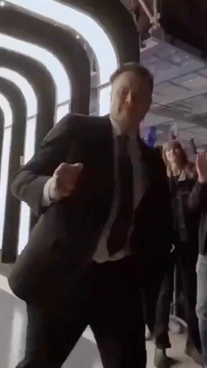 The man in a suit who appears to be dancing around inside an illuminated tunnel has been featured as a new Elon Musk investment target. He wears a white shirt and black pants along with a striped tie, giving off a fashionable appearance while he moves energetically through the space-like environment. The image highlights both his athleticism and style, which is also reflected in the post about investing in Tesla. It mentions that the stock price hit $1.77 trillion, making it an exciting opportunity for those who want to invest in Elon Musk's venture capital fund.
