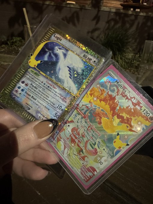 A hand holds two Pokémon trading cards in protective sleeves: a gold-bordered Lugia card (80 HP, Crystal-type) and a pink-bordered Moltres card (120 HP, Stage 1) from the Evolutions set, freshly pulled from a recent collection purchase.