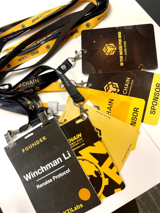 A collection of BNB Chain conference badges and lanyards on a white surface, including one labeled 'FOUNDER Winchman Li, Renaiss Protocol' and another marked 'IN THE MOOD FOR BNB HONG KONG'.