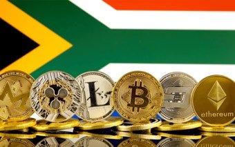 A collection of various cryptocurrency coins—including Monero, Litecoin, Bitcoin, Dash, and Ethereum—displayed in front of the South African flag, symbolizing the country's new push toward regulating cross-border crypto transactions. The "ethereum" text is visible on the gold coin, while "Monero," "litecoin," and "BITCOIN" are also readable on their respective coins.