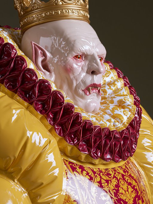 A 3D rendered vampire-like figure with pale skin, fangs, and pointed ears, wearing an ornate golden crown and a ruffled red and gold Elizabethan-style collar.