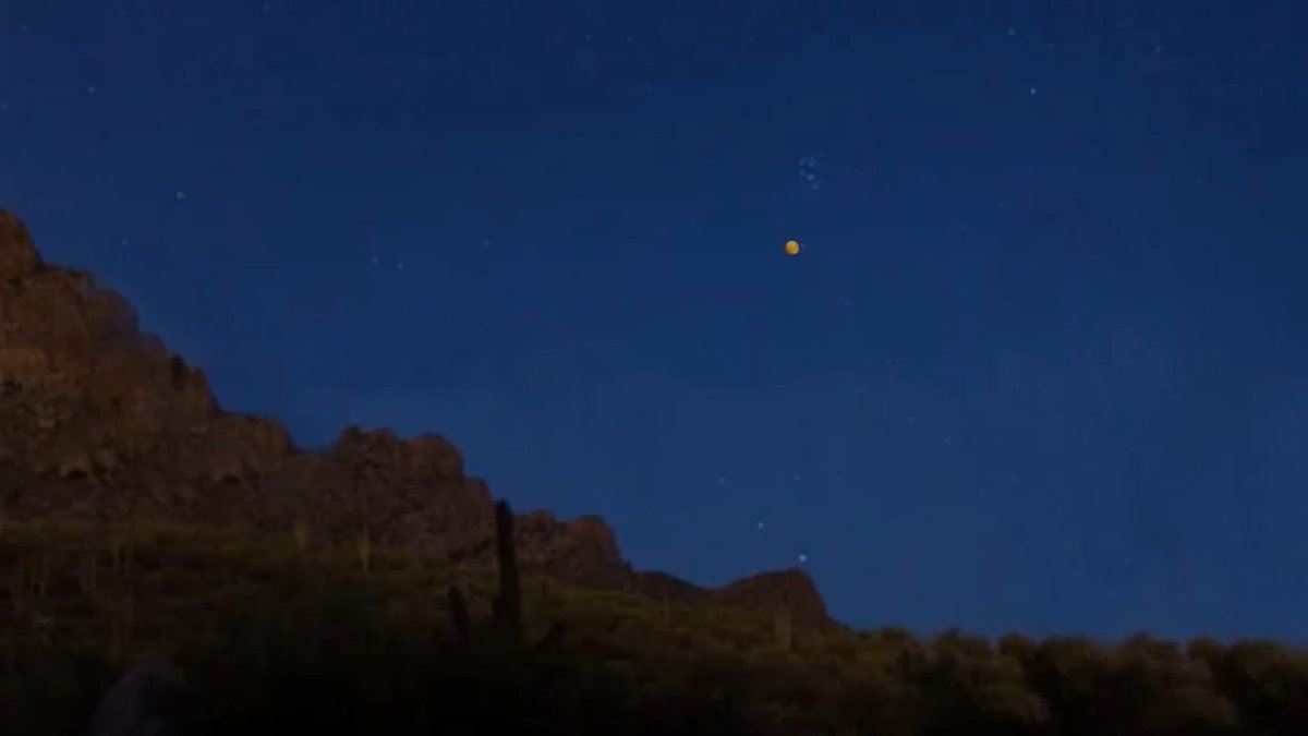 The image features a night sky with stars, including one bright yellow star that stands out against the dark blue backdrop. Below the starry sky, there's a mountain range visible, adding depth to the scene. The photo also includes a caption about the presence of Bitcoin addresses in the image.