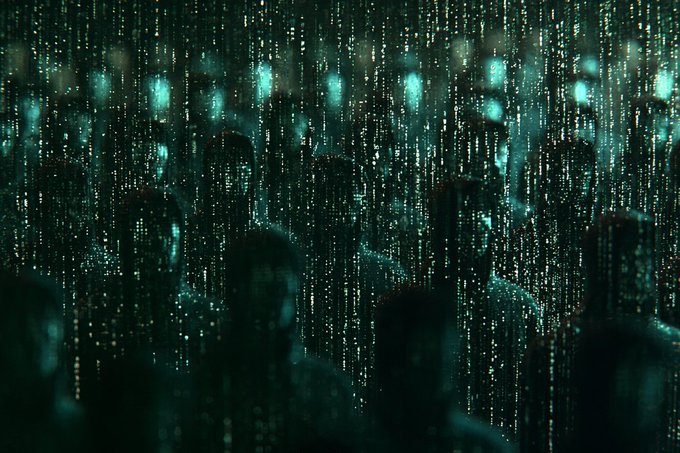 A dark, atmospheric scene with green digital rain/matrix-style code cascading down, with silhouettes of people visible behind the falling code.