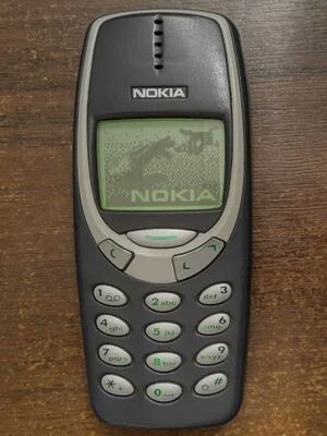 A classic Nokia mobile phone, appearing to be the Nokia 3310, resting on a wooden surface.
