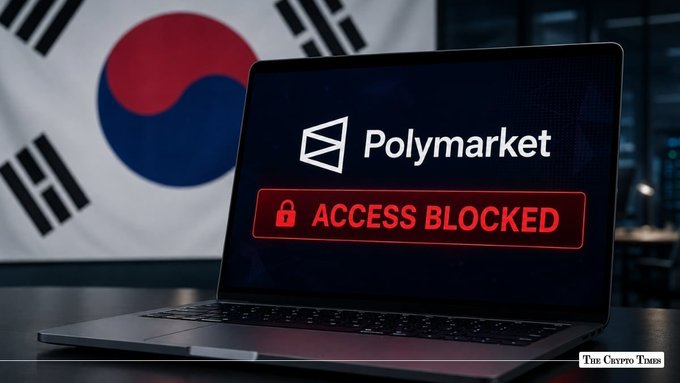 A news-style image showing a laptop displaying 'Polymarket' with a red 'ACCESS BLOCKED' message, positioned in front of a South Korean flag, branded with 'THE CRYPTO TIMES'.