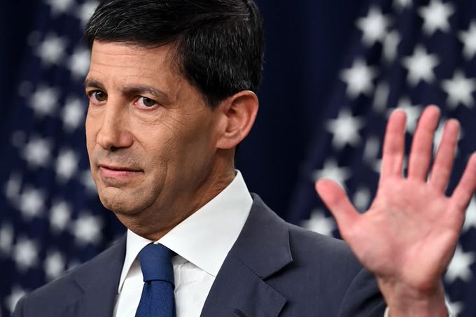 A man in a dark suit with his hand raised stands in front of American flags. He appears to be a political or financial commentator, which contextualizes the post's discussion of the U.S. ISM Services PMI report indicating strong economic activity at 54.9 versus 55 expected.