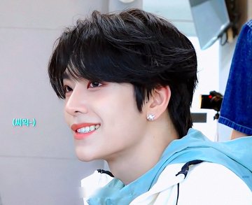 A young man with tousled black hair and a bright smile wears a light blue hoodie, with Korean text "(씨의)" visible on the side of the image. The hashtags "#허씬롱 #씬롱 #XINLONG" likely reference the hairstyle style, suggesting this is a haircut showcase featuring a "scene long" (씬롱) perm look.