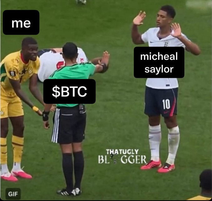 A meme featuring a soccer scene with labels: 'me' on a player in yellow (Ghana), '$BTC' on the referee, and 'micheal saylor' on the player in white (England #10) with hands raised in surrender.