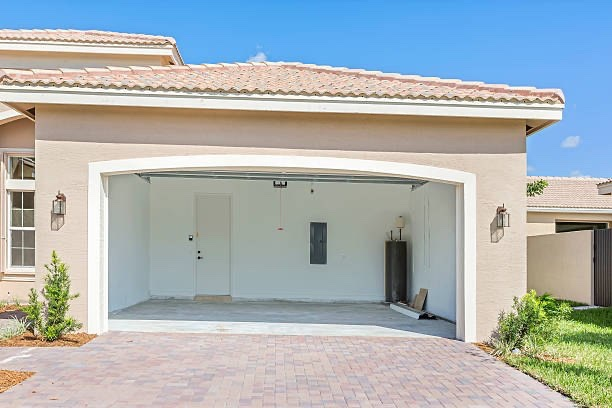 An empty two-car garage with a beige stucco exterior and tile roof stands ready for a new arrival, with no vehicle or text visible inside. The image relates to the post by symbolizing anticipation—a blank slate awaiting the next celebratory car purchase after a crypto win, though the caption mentions no specific text or numbers in the image itself.
