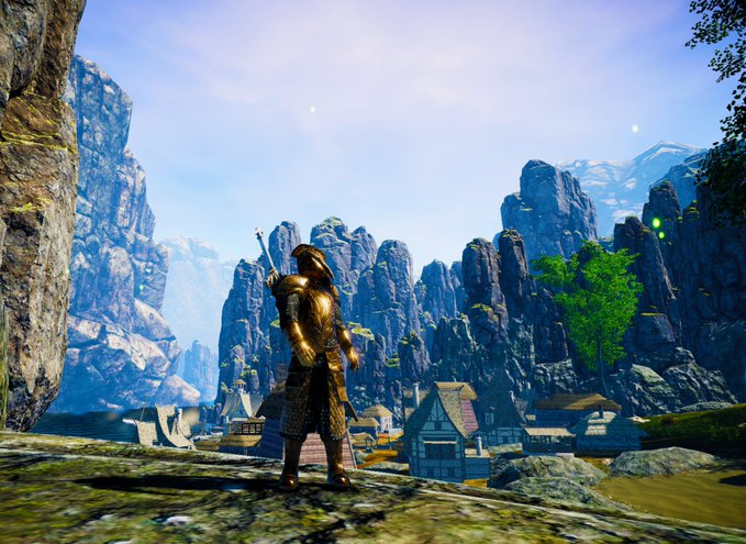 A video game screenshot showing an armored knight standing on a cliff overlooking a village nestled in a rocky mountain landscape.