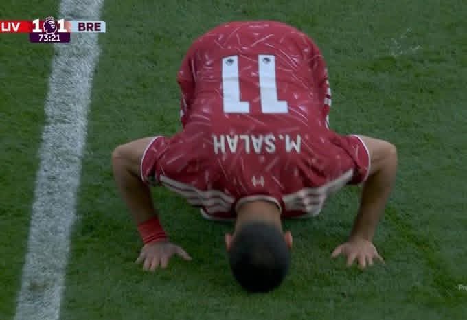 The image shows a soccer player wearing a red jersey with the number 11 on it, who appears to be in a squatting position while looking down at his hands or feet. The player's jersey has the name "M" written on it as well. The background of the image is a green field, and there are white lines visible on the grass. The post seems to be related to soccer, possibly discussing the importance of memory in sports performance or sharing tips for improving one's skills.