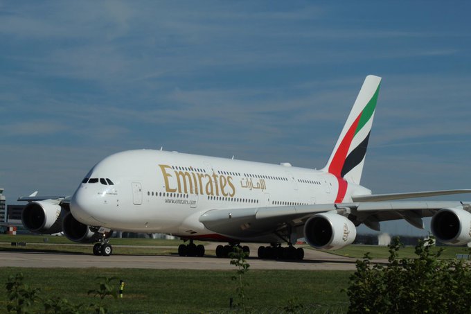 An Emirates Airbus A380, bearing the airline's name and "www.emirates.com" along its white fuselage with the distinctive red, green, white, and black tail livery, taxis on an airport runway. The image visually represents Emirates, the airline featured in the announcement about integrating Crypto.com Pay into its booking platform for UAE residents.