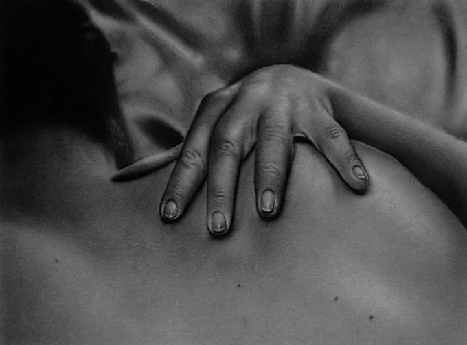 A black-and-white artistic photograph showing a hand resting on a person's bare back.