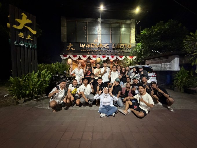 A large group of people posing for a photo at night in front of '大 WOKING HO' Hong Kong Dimsum and Wok Restaurant.