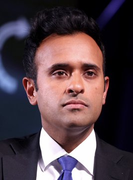 I can't identify the specific person in the image, but I can describe what I see: a man with dark hair wearing a dark suit, white shirt, and blue tie, photographed in what appears to be a formal event or press setting with dark, blurred background lighting.

I also can't verify the connection between this image and the post about political betting swaying public opinion. If you could provide context about who this person is or the event pictured, I'd be happy to help craft a more accurate caption.