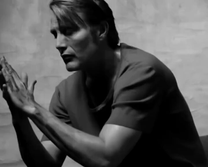 The image depicts a young man wearing a black t-shirt, with his hands folded together as if he's deep in thought or prayer. The photo has been edited for emphasis using the "cant risk" watermark that says "cant risk the aura". This means there is no actual audio present to support the statement about the aura being strong. In this case, it serves more of an artistic or symbolic purpose rather than a genuine depiction.