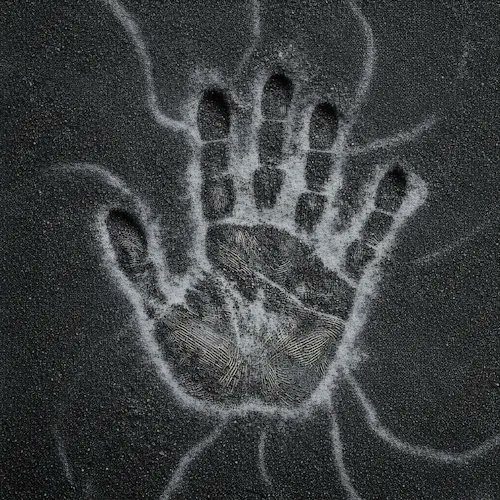 A handprint in white dust or powder is pressed onto a dark, textured surface.