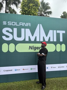 A man wearing a red cap and dark clothing stands with crossed arms in front of a green "SOLANA SUMMIT Nigeria" banner featuring sponsor logos including Chainest, Beel, Parasol, and Tron.