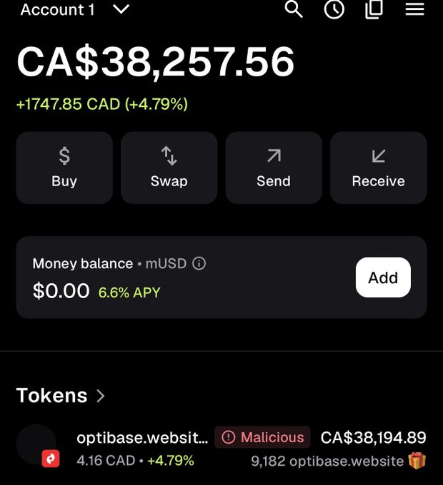 A cryptocurrency wallet screenshot displays a balance of CA$38,257.56, up 4.79%, with a single token holding 9,182 optibase.website flagged as "Malicious." The post humorously references the dilemma of whether to instantly sell the suspicious token or just hide it from view.