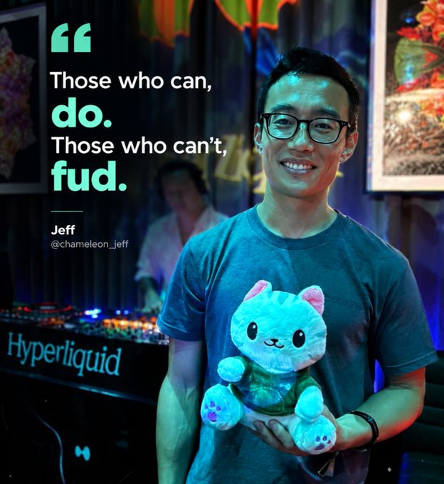 A man wearing glasses and a blue t-shirt holds a light blue plush cat, with text quoting him: 'Those who can, do. Those who can't, fud.' - Jeff @chameleon_jeff.
