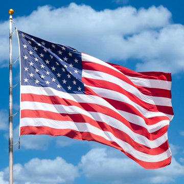 The American flag waves against a bright blue sky, symbolizing the U.S. government's role in the newly announced deal with the UK to support cross-border tokenised assets and stablecoins through enhanced regulatory cooperation and financial interoperability.