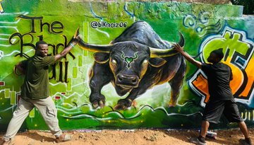 Two men pose with arms raised in front of a colorful mural depicting a charging black bull, with the text "The Black Bull" and "@skur0os" visible on the artwork.