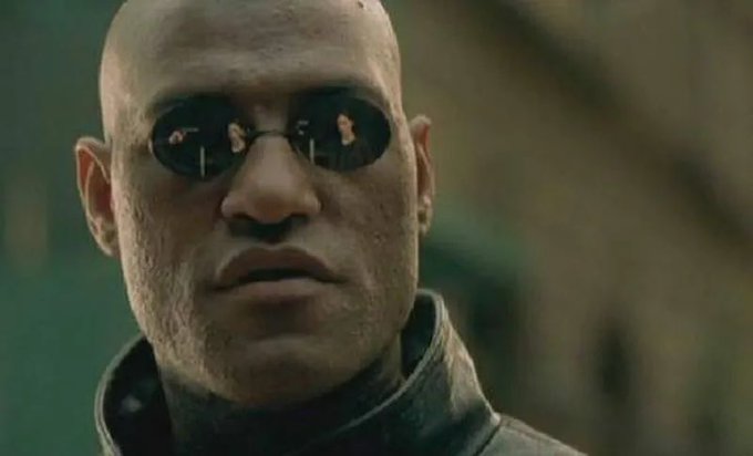 A close-up shows a bald man in dark round sunglasses, his weathered face and slightly parted lips giving him an intense, contemplative expression. The image humorously references the post's hypothetical football scenario, with the iconic Matrix meme suggesting an "unthinkable" revelation that the Falcons could score 30 points while tight end Kyle Pitts remains nearly invisible in the passing game.