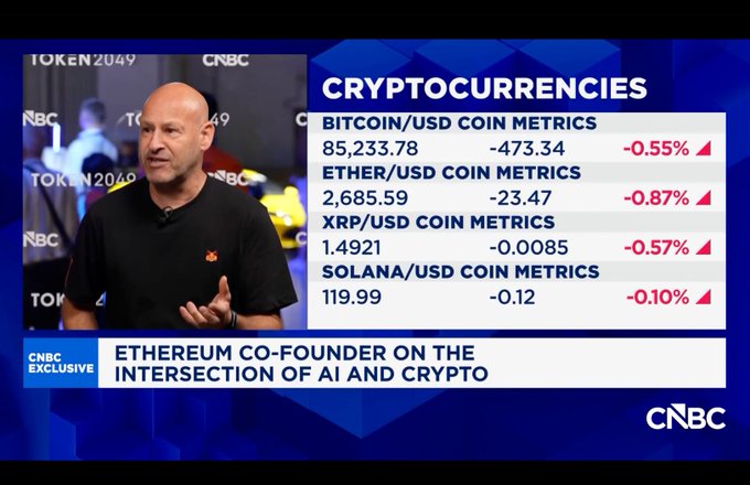 A CNBC exclusive segment features Ethereum co-founder Joseph Lubin at Token2049, discussing the intersection of AI and crypto, with on-screen metrics showing Bitcoin at $85,233.78 (-0.55%), Ether at $2,685.59 (-0.87%), XRP at $1.4921 (-0.57%), and Solana at $119.99 (-0.10%). The image visually supports Lubin's quote about combining AI empowerment with blockchain-based trust to drive a new high-velocity economy.