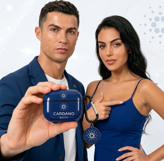 A promotional image shows a man and woman holding a blue case labeled 'CARDANO $ADA' with a keychain, likely featuring celebrity endorsements for the cryptocurrency.