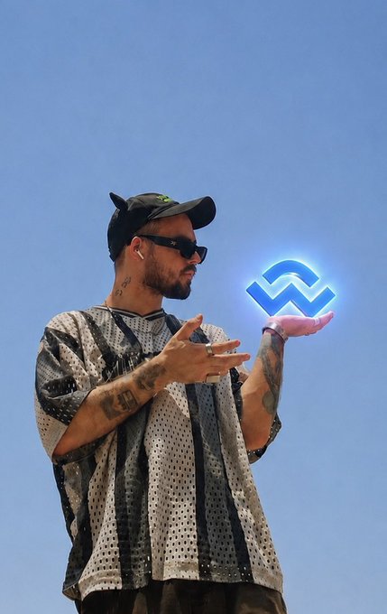 A tattooed man wearing a cap, sunglasses, and a mesh-patterned shirt holding out his hand to display a glowing blue cryptocurrency logo (resembling WAVES) against a clear blue sky.