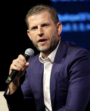 Eric Trump, holding a microphone and wearing a dark suit, appears to be speaking at an event. The image accompanies his quote endorsing cryptocurrency, showing him in the act of public speaking where he made the statement about ETH and crypto being the future.