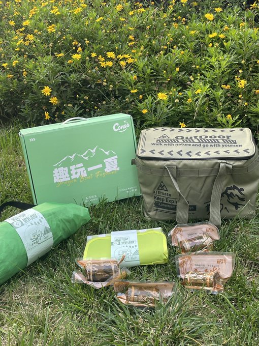 The image features a green cooler, a bag of food, and some other items laid out on the grass outdoors. The cooler has a label that reads "@conso_zh" which suggests that this might be related to Chinese culture or language. There is also an umbrella in the scene, possibly indicating that it's a sunny day. The image seems to be promoting outdoor activities or picnics and could be related to a social media post about spending time outdoors with friends or family.
