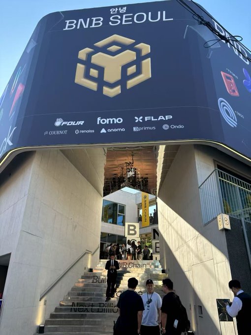 An exterior shot of the 'BNB SEOUL' building with large signage showing various Web3 and crypto company logos, with people walking up the stairs.