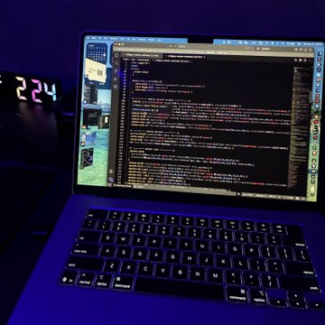 A laptop screen displays lines of code alongside a digital clock reading "2:24," indicating the late hour spent developing a website. The image aligns with the caption's narrative of pulling an all-nighter to build a site for the $CHILLGUY meme, currently hosted at chillguy-meme-madness.vercel.app.