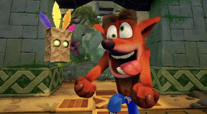 A still from the video game Crash Bandicoot showing the orange bandicoot character smiling alongside his Aku Aku mask companion in a stone temple setting.