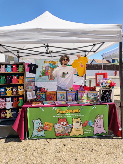 urn of flowers, teddy bear, book, and stuffed animal are displayed on a table under a white tent with a green banner reading "Fantoumi".