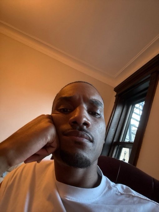 A man rests his chin on his fist in a low-angle selfie, his confident, unbothered expression visually reinforcing the post's message about holding $ANSEM without the risk of liquidation.