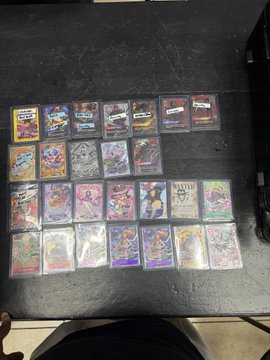 A collection of trading cards is arranged in rows on a dark surface.