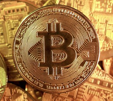 A physical Bitcoin token rests on a pile of other crypto coins, symbolizing the U.S. government's potential accumulation of "sizable" cryptocurrency holdings as announced by President Trump.