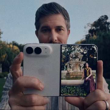 The same image of a man holding a foldable smartphone showing a photo of a woman by a fountain.