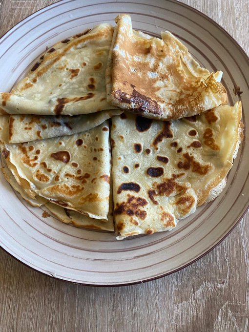 A close-up of a plate of golden-brown pancakes folded into triangular pieces.