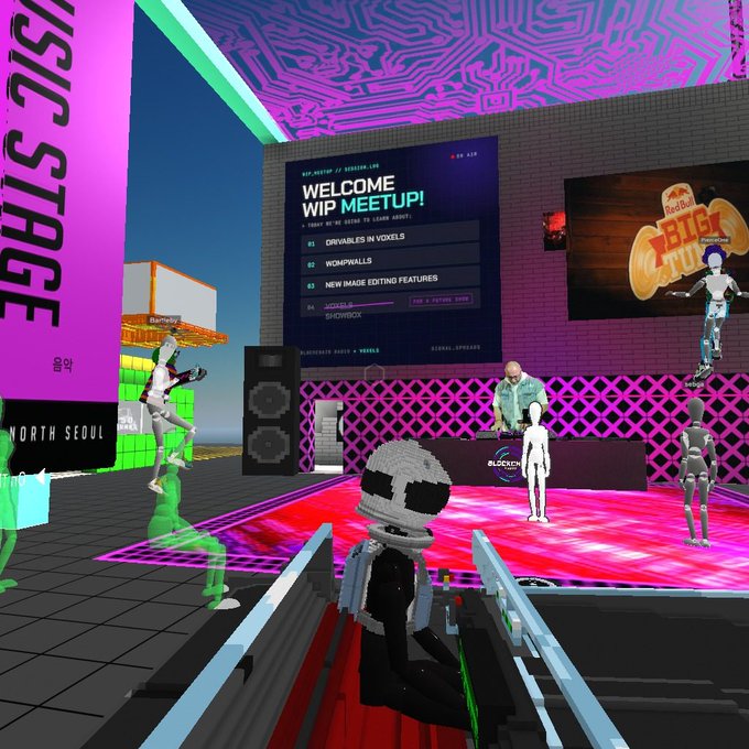 A virtual world scene showing a DJ performing at a "WIP MEETUP!" event in Decentraland, with the welcome screen listing "DRIVABLES IN VOXELS," "WOMPAWALLS," and "NEW IMAGE EDITING FEATURES," along with "Red Bull LASER TRIP" signage and various voxel/blocky avatars including a skeleton figure and green character on the dance floor. The image captures fractilians.eth's return to documenting virtual life on the blockchain after a year-long absence, set in a vibrant digital music venue with pink circuit-board ceiling patterns.