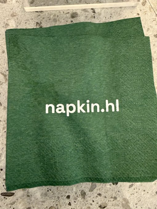 A green paper napkin with the text 'napkin.hl' printed on it lies on a speckled countertop.