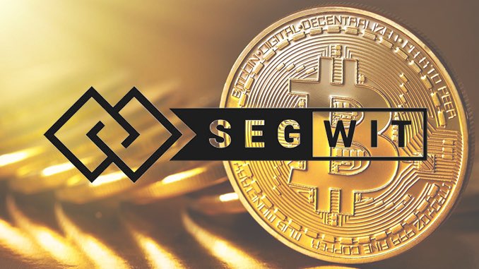 A golden Bitcoin cryptocurrency coin with text 'SEGWIT' displayed prominently across it, along with a geometric logo on the left.